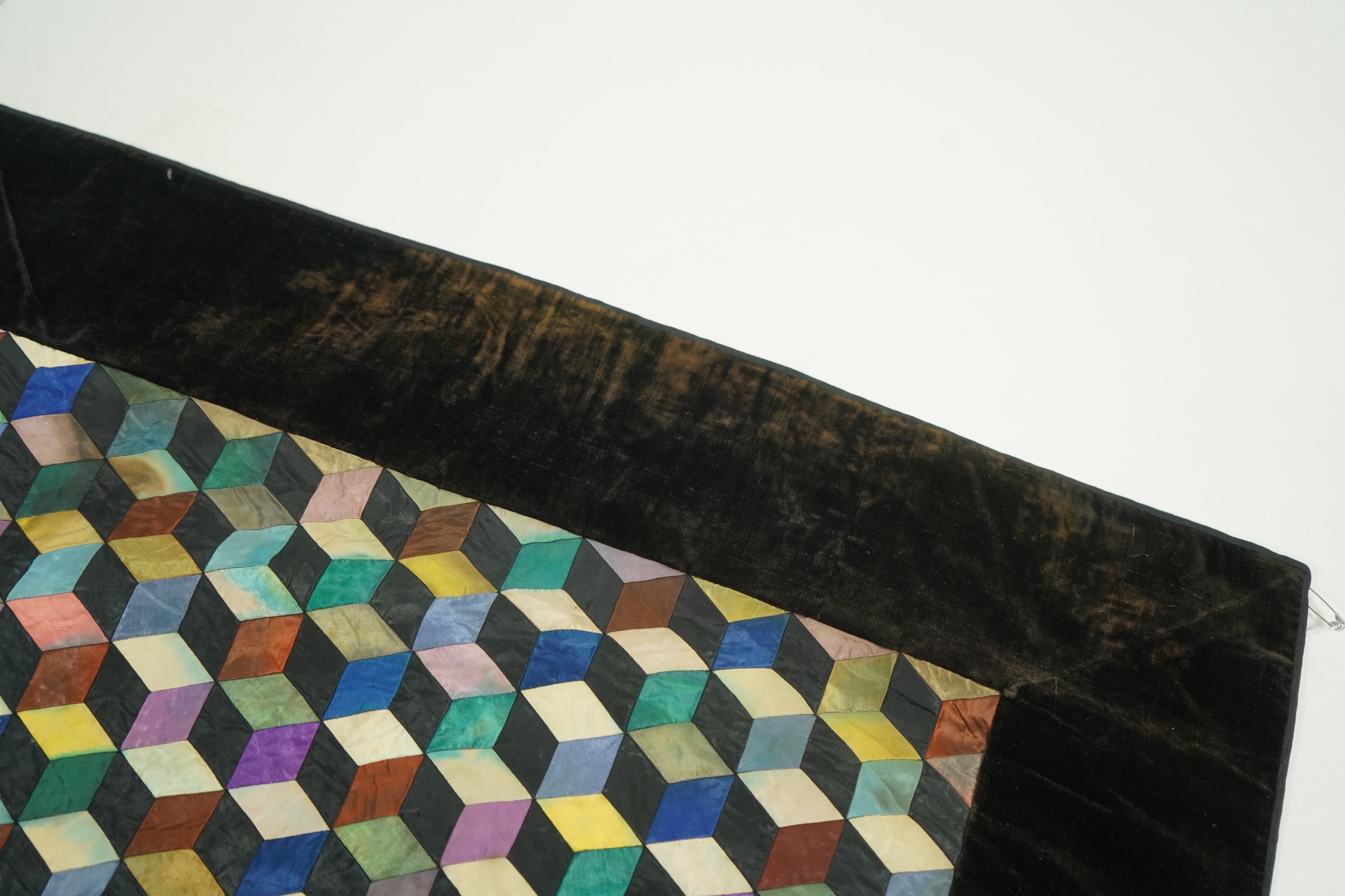 An English 19th century silk ‘Tumbling Blocks’, hand sewn, patchwork quilt, with central star motif and wide velvet border. Worked with multi coloured silks backed with black and blue silk., 170cm x 152cm. Condition - th